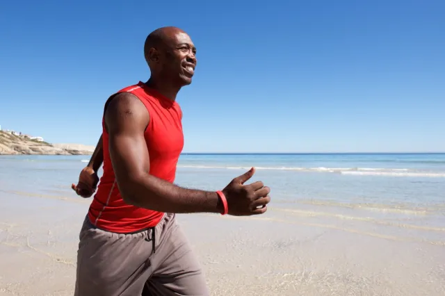 A middle-aged man walking on the beach on a sunny day is fit